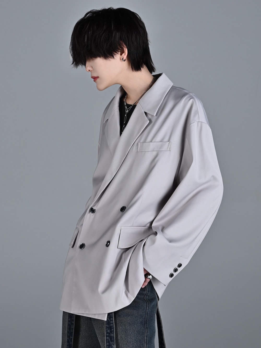 ブルー系のデニムパンツ、レッド系のタンクトップ、グレー系のテーラードジャケットを着用したメンズの冬コーディネートの3枚目の写真