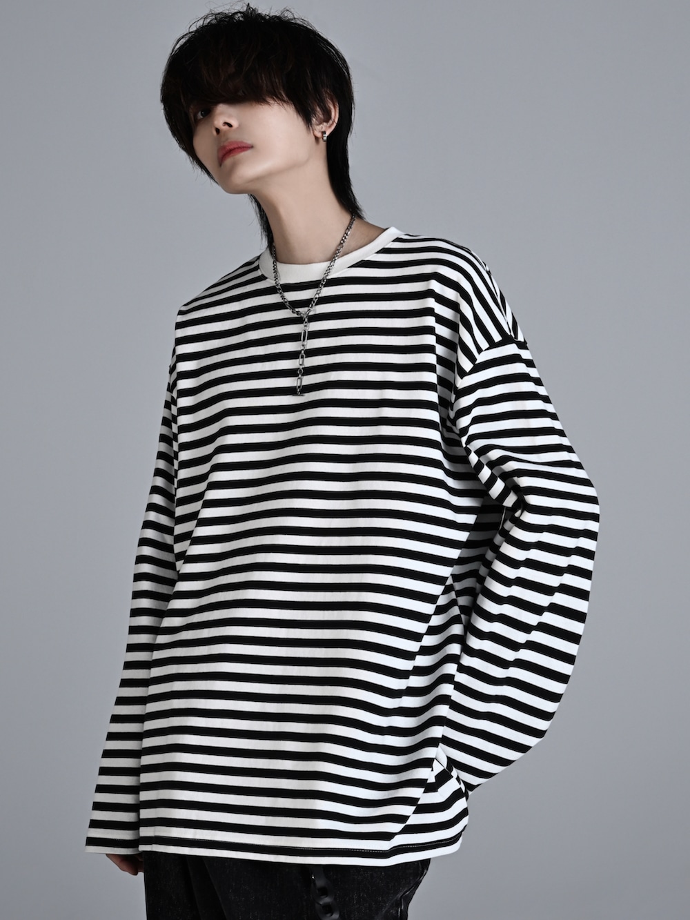 ブラック系のデニムパンツ、ホワイト系のスニーカー、ブラック系のショルダーバッグを着用したメンズの秋コーディネートの3枚目の写真