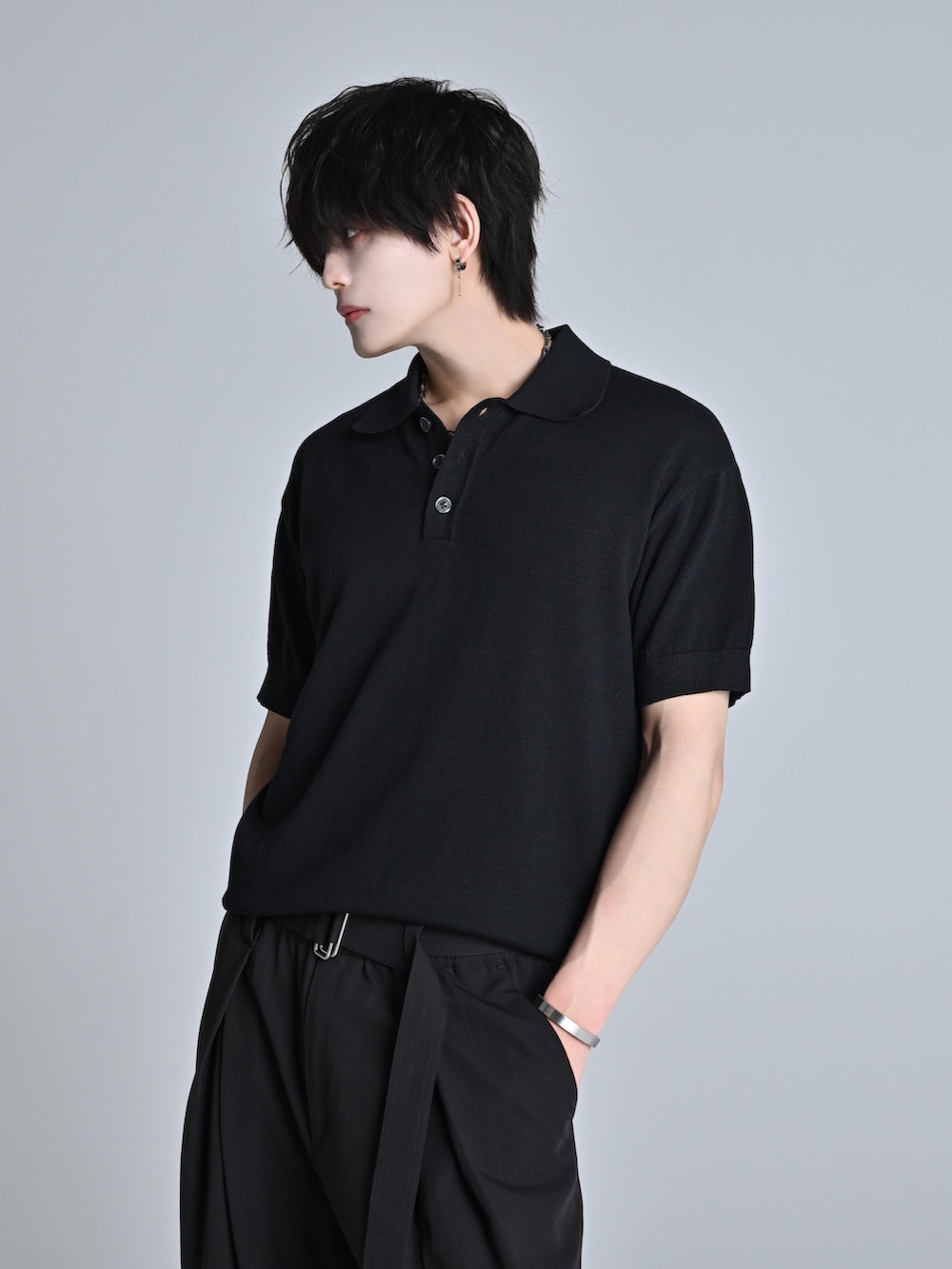 ブラック系のデニムパンツ、ブラック系のポロシャツ、ブラック系のブーツを着用したメンズの春コーディネートの4枚目の写真