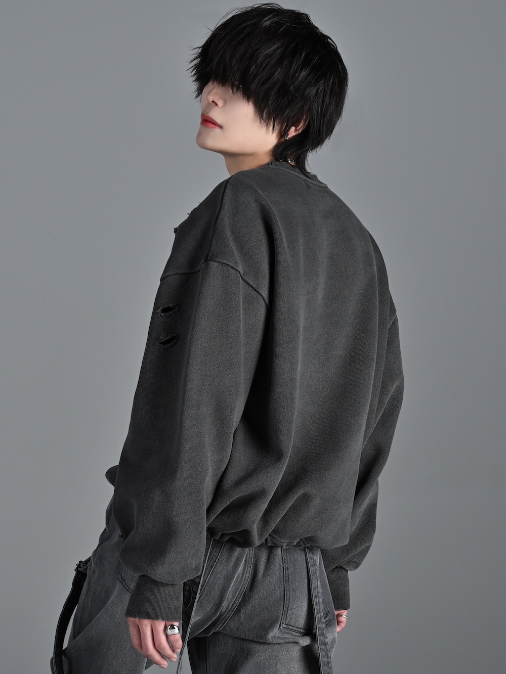 グレー系のスウェット、グレー系のデニムパンツ、シルバー系のネックレスを着用したメンズの冬コーディネートの3枚目の写真