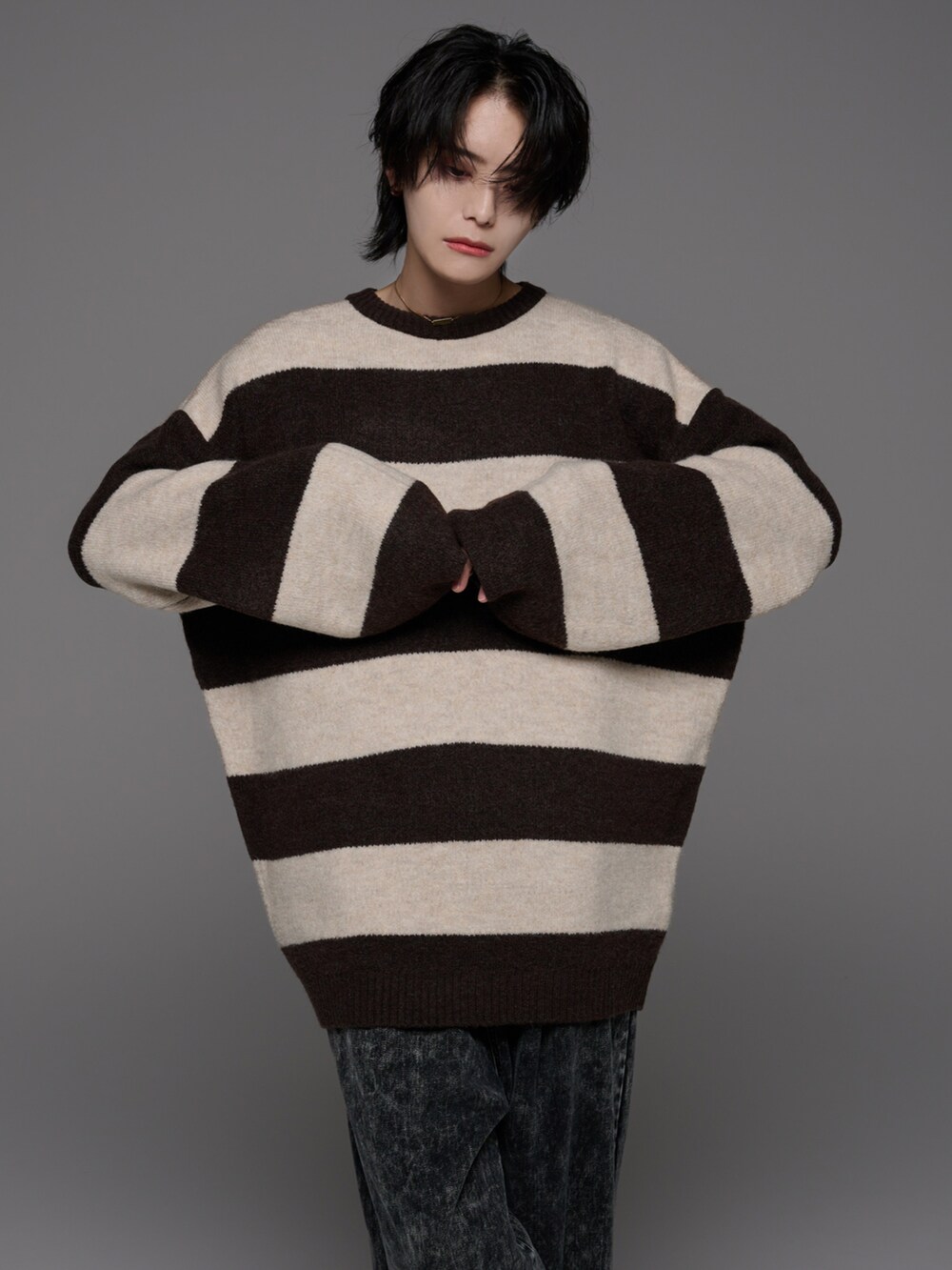 ブラック系のデニムパンツ、ホワイト系のスニーカー、ブラウン系のニット/セーターを着用したメンズの秋コーディネートの2枚目の写真