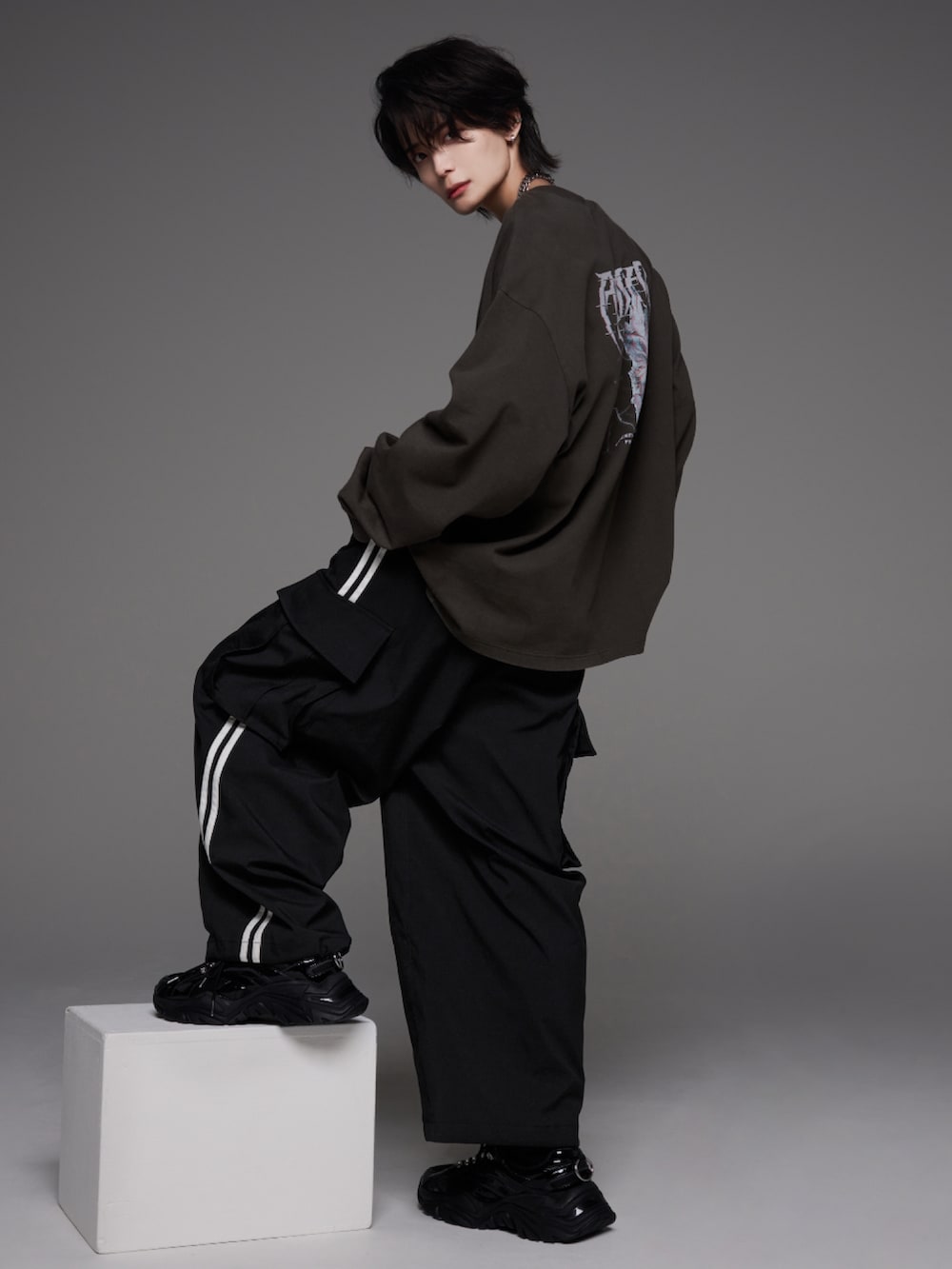 ブラック系のスニーカー、グレー系のTシャツ/カットソー、ホワイト系のカーゴパンツを着用したメンズの秋コーディネートの2枚目の写真