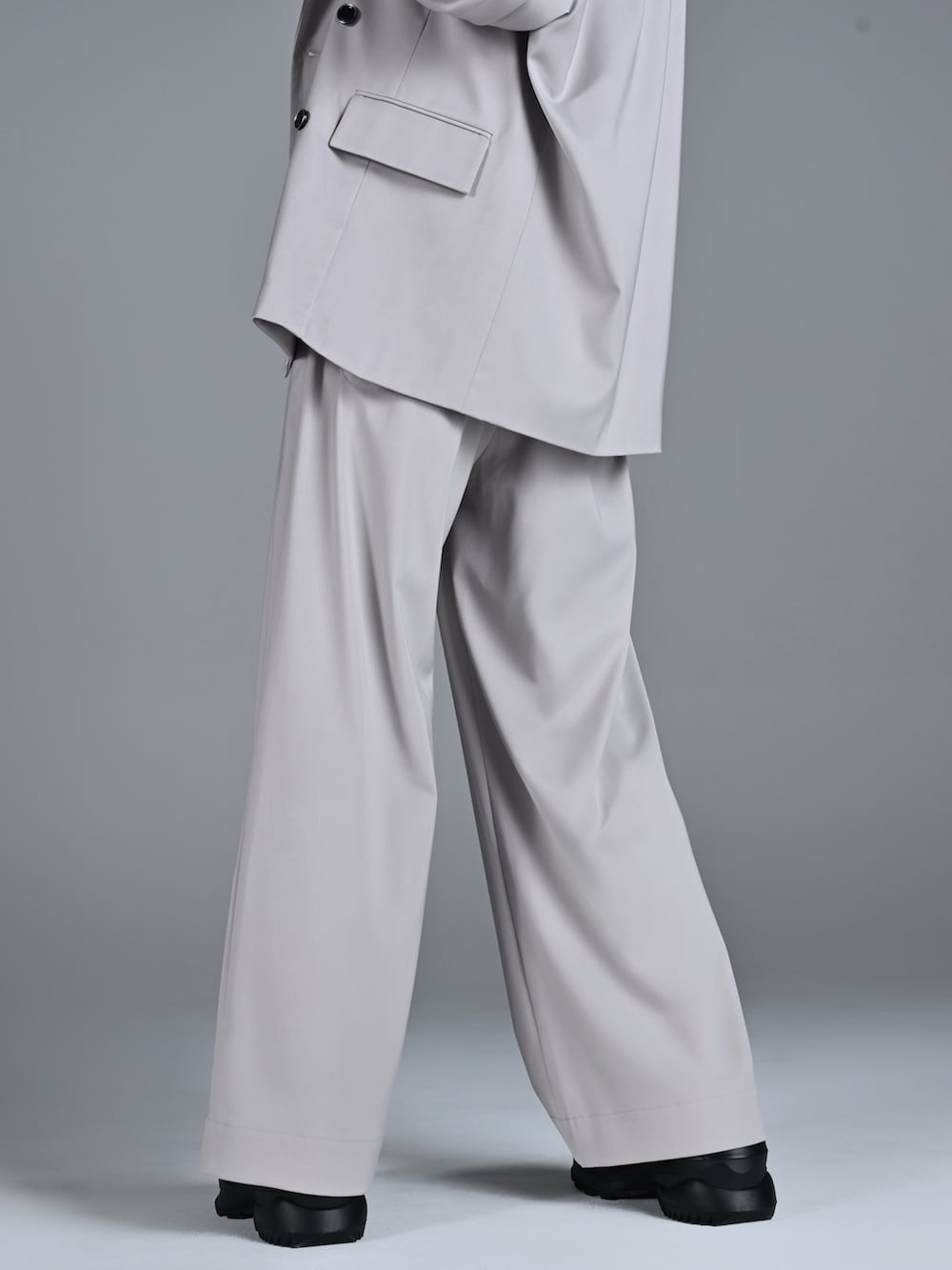 ホワイト系のスニーカー、レッド系のタンクトップ、グレー系のテーラードジャケットを着用したメンズの冬コーディネートの4枚目の写真