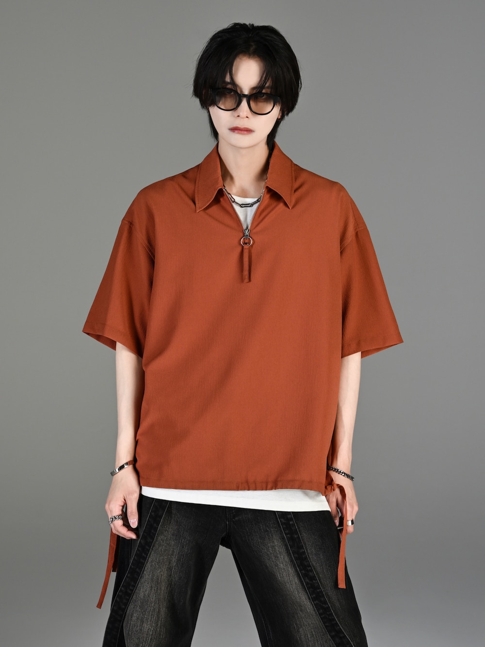 グレー系のタンクトップ、ブラック系のデニムパンツ、ホワイト系のスニーカーを着用したメンズの春コーディネートの2枚目の写真