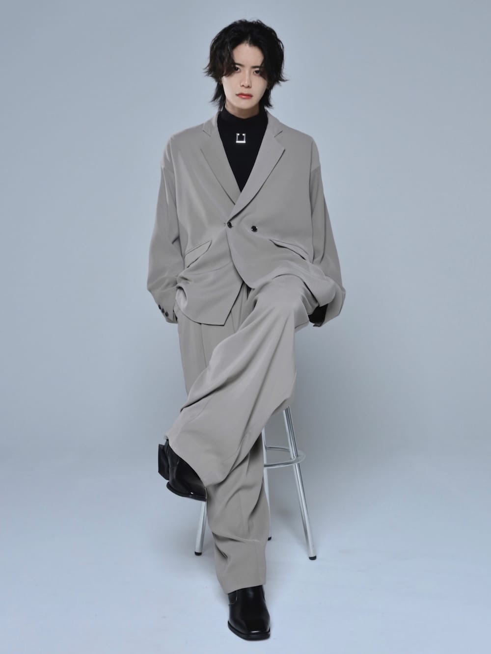 ブラック系のブーツ、ブラック系のTシャツ/カットソー、ベージュ系のテーラードジャケットを着用したメンズの冬コーディネートの2枚目の写真