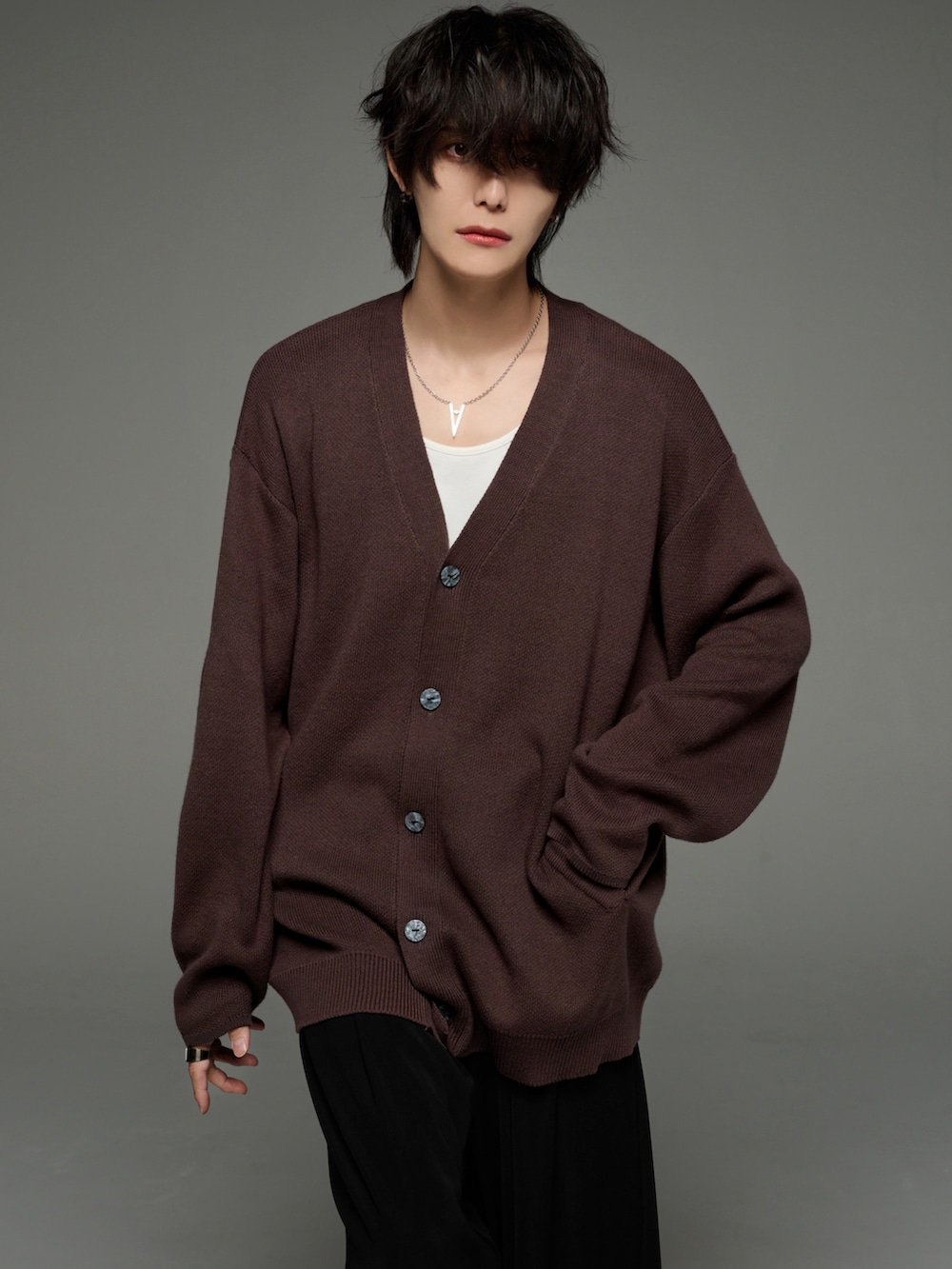 ブラック系のスラックス、ブラック系のブーツ、ブラウン系のカーディガン/ボレロを着用したメンズの秋コーディネートの5枚目の写真