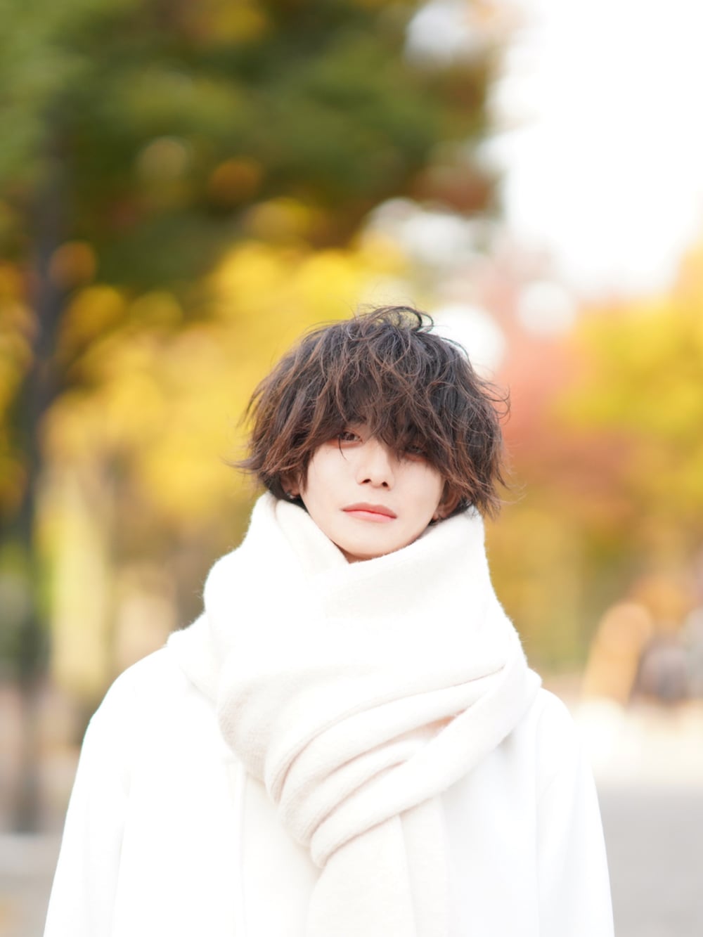 ブルー系のデニムパンツ、グリーン系のニット/セーター、ベージュ系のトートバッグを着用したメンズの秋コーディネートの5枚目の写真