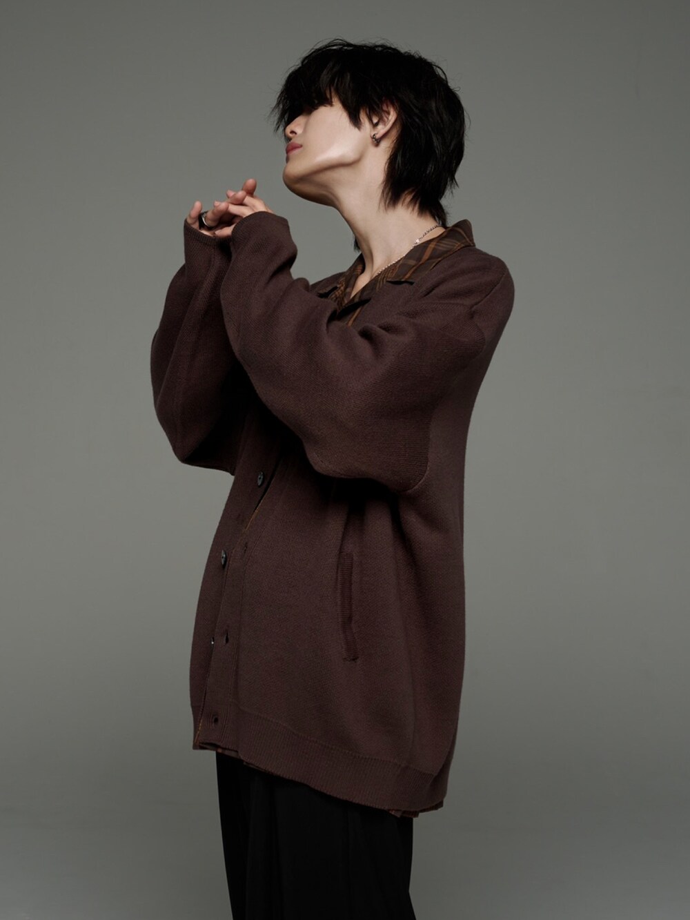 ブラック系のスラックス、ブラック系のブーツ、ブラウン系のカーディガン/ボレロを着用したメンズの秋コーディネートの3枚目の写真