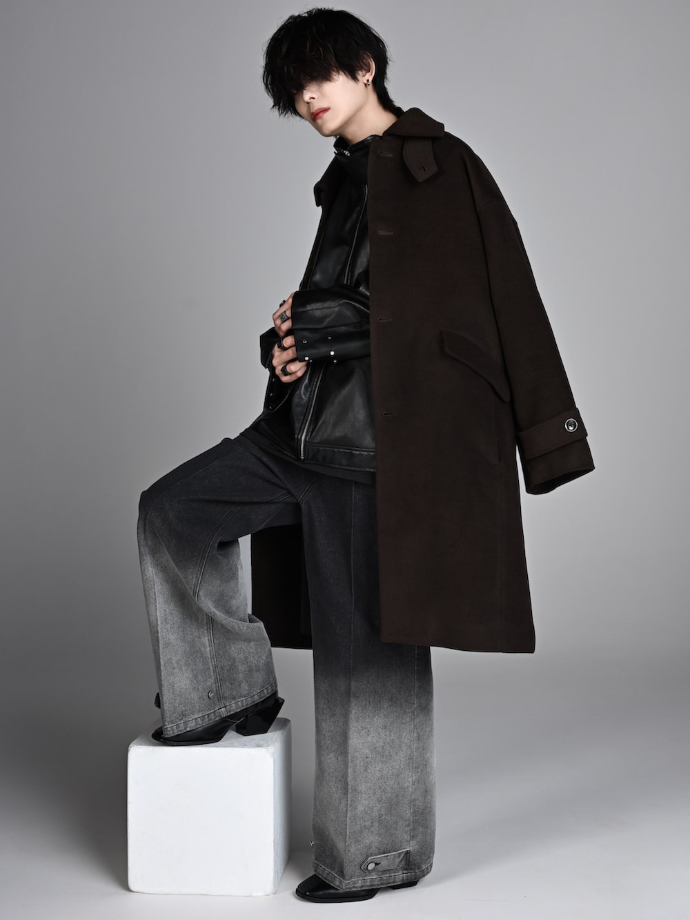 ブラック系のタンクトップ、ブラック系のブーツ、ブラウン系のステンカラーコートを着用したメンズの秋コーディネートの2枚目の写真