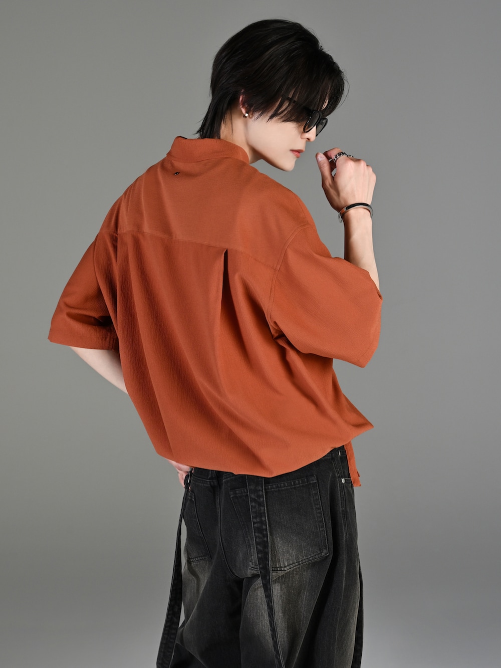 グレー系のタンクトップ、ブラック系のデニムパンツ、ホワイト系のスニーカーを着用したメンズの春コーディネートの5枚目の写真