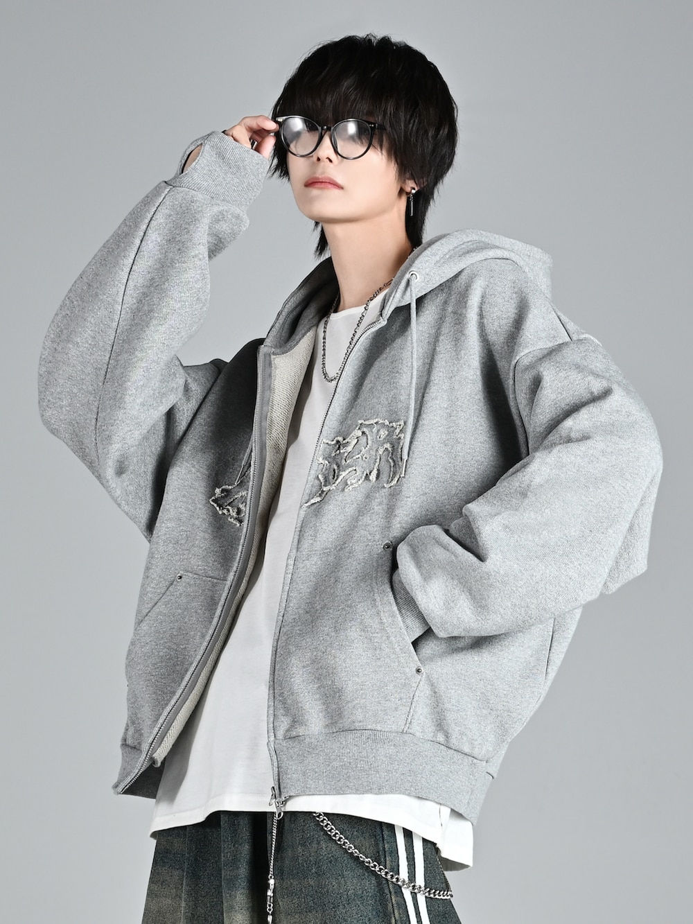 レッド系のタンクトップ、グレー系のパーカー、ブルー系のデニムパンツを着用したメンズの秋コーディネートの5枚目の写真