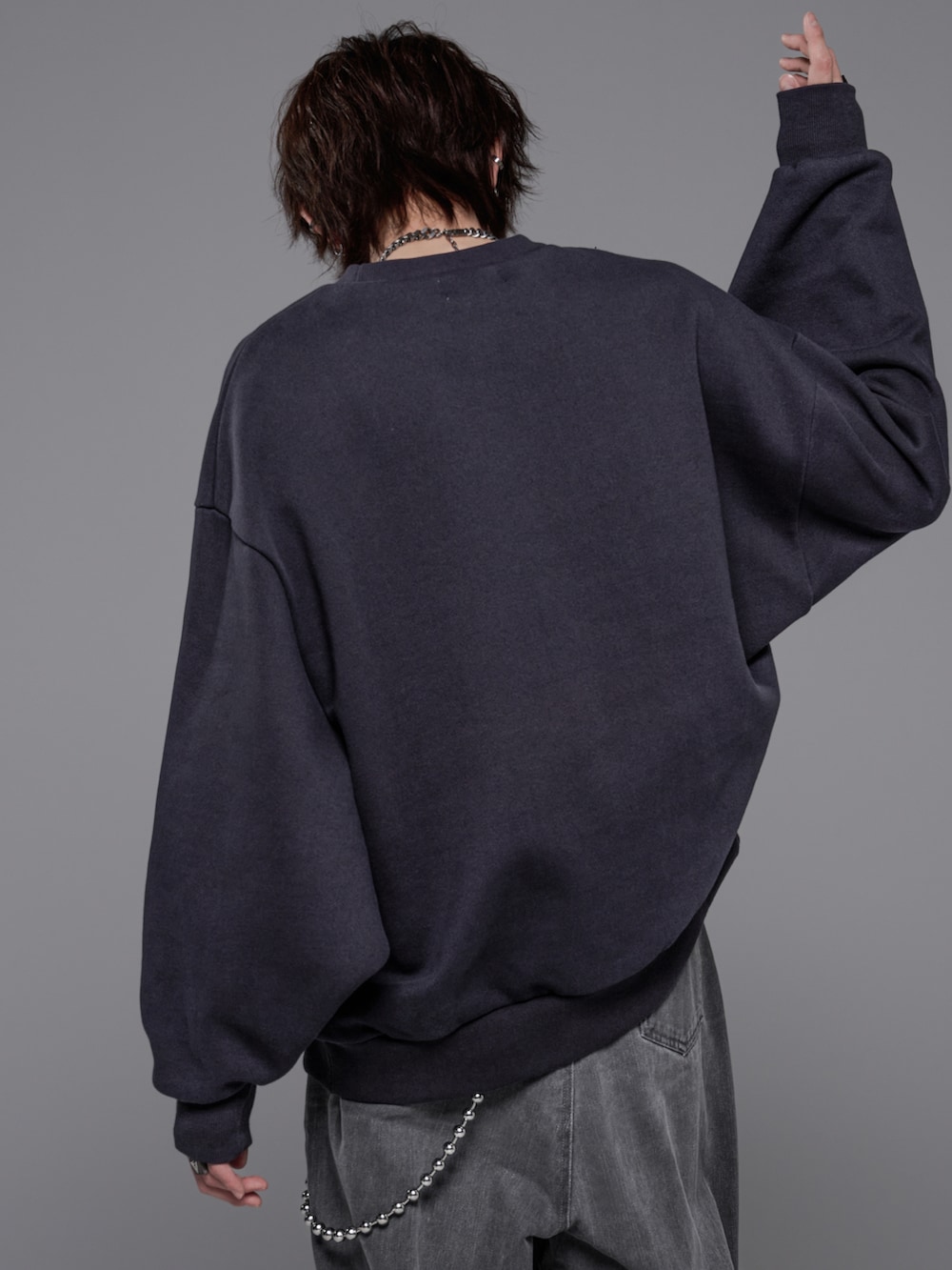 グレー系のデニムパンツ、グレー系のスウェット、ブラック系のブーツを着用したメンズの冬コーディネートの5枚目の写真