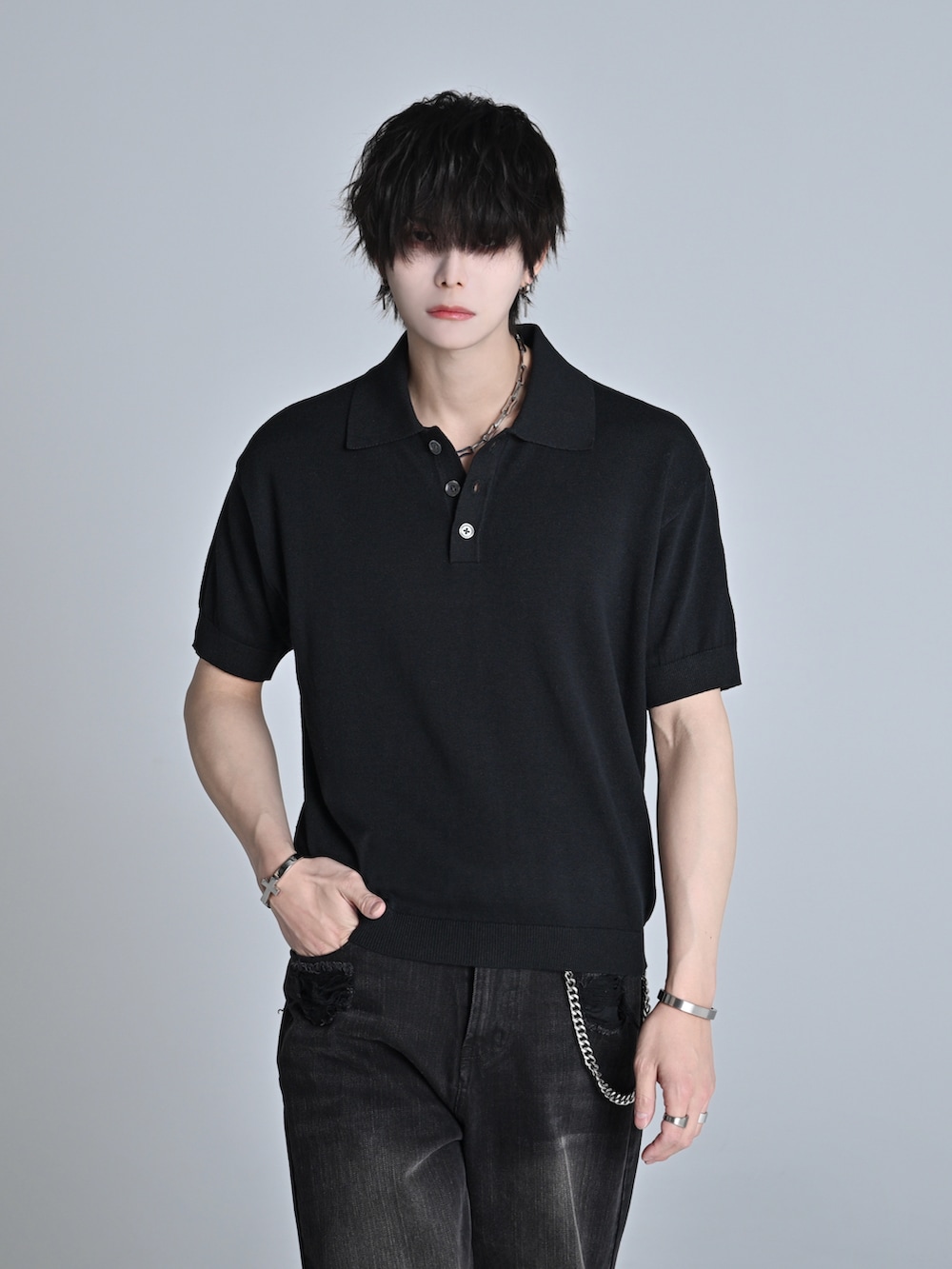 ブラック系のデニムパンツ、ブラック系のポロシャツ、ブラック系のブーツを着用したメンズの春コーディネートの2枚目の写真