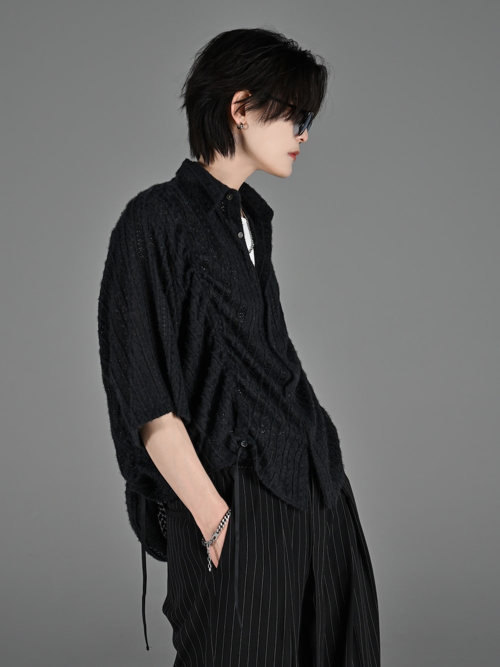 ブラック系のブーツ、グレー系のタンクトップ、ブラック系のスラックスを着用したメンズの春コーディネートの5枚目の写真