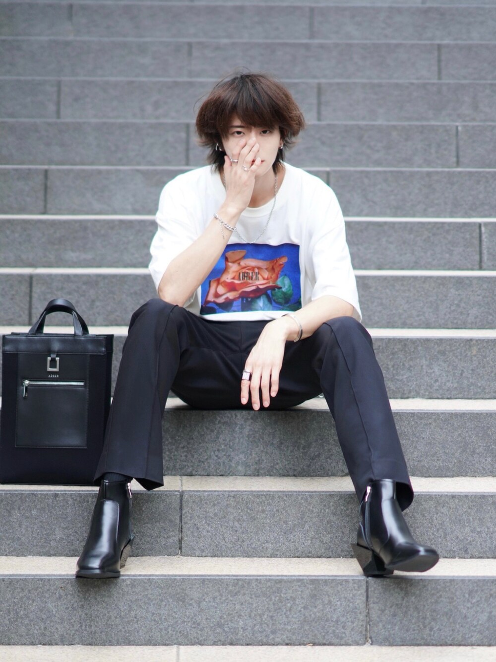 ホワイト系のTシャツ/カットソー、ブラック系のスラックス、ブラック系のブーツを着用したメンズの夏コーディネートの4枚目の写真