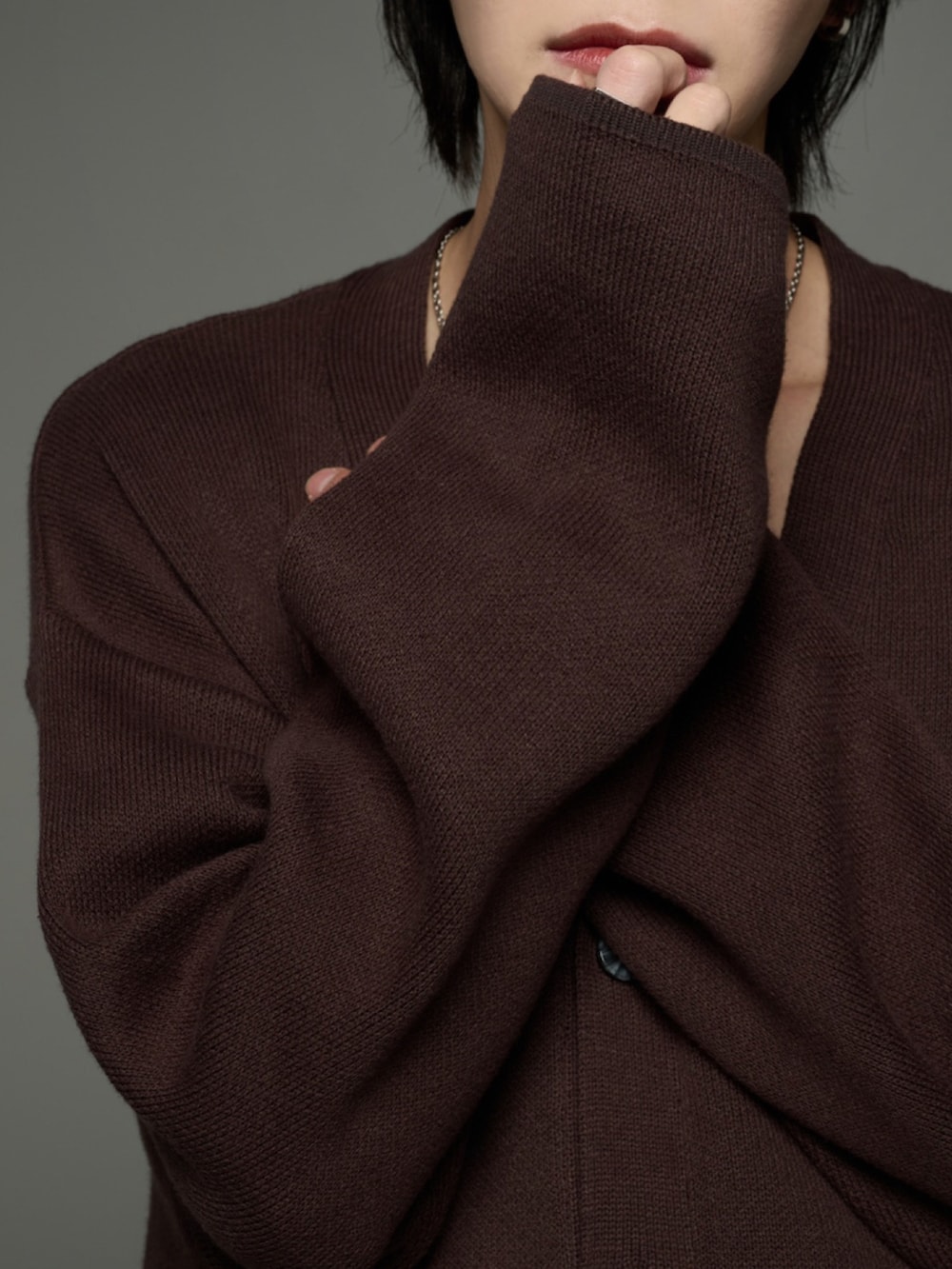 ブラック系のスラックス、ブラック系のブーツ、ブラウン系のカーディガン/ボレロを着用したメンズの秋コーディネートの4枚目の写真