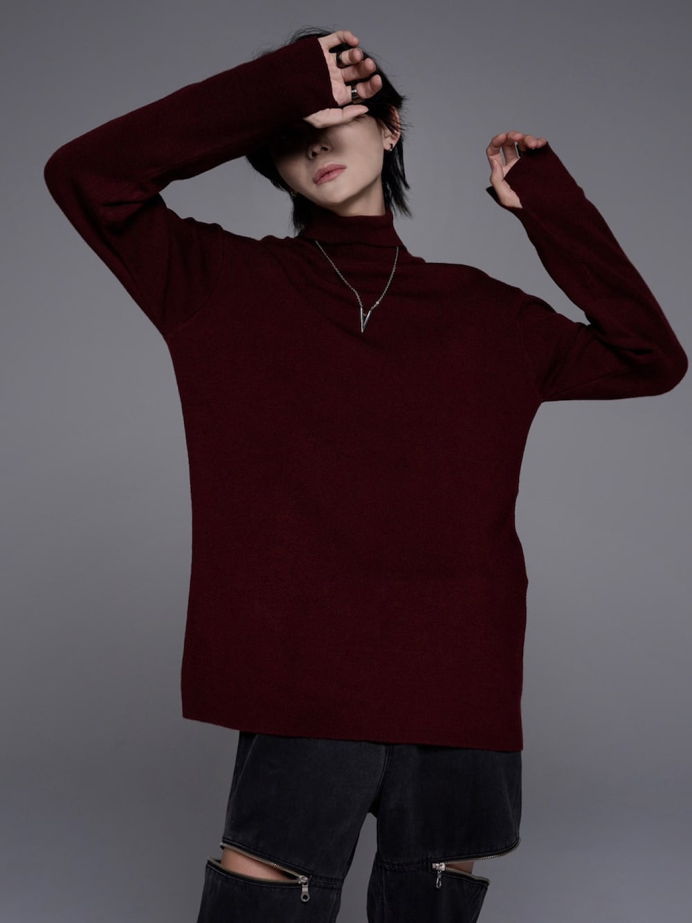 ブラック系のスニーカー、ブラック系のニット/セーター、グレー系のデニムパンツを着用したメンズの秋コーディネートの4枚目の写真