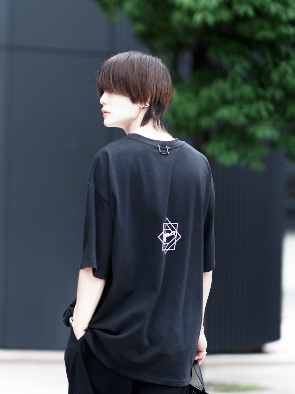 ブラック系のトートバッグ、ブラック系のスラックス、ブラック系のブーツを着用したメンズの夏コーディネートの5枚目の写真