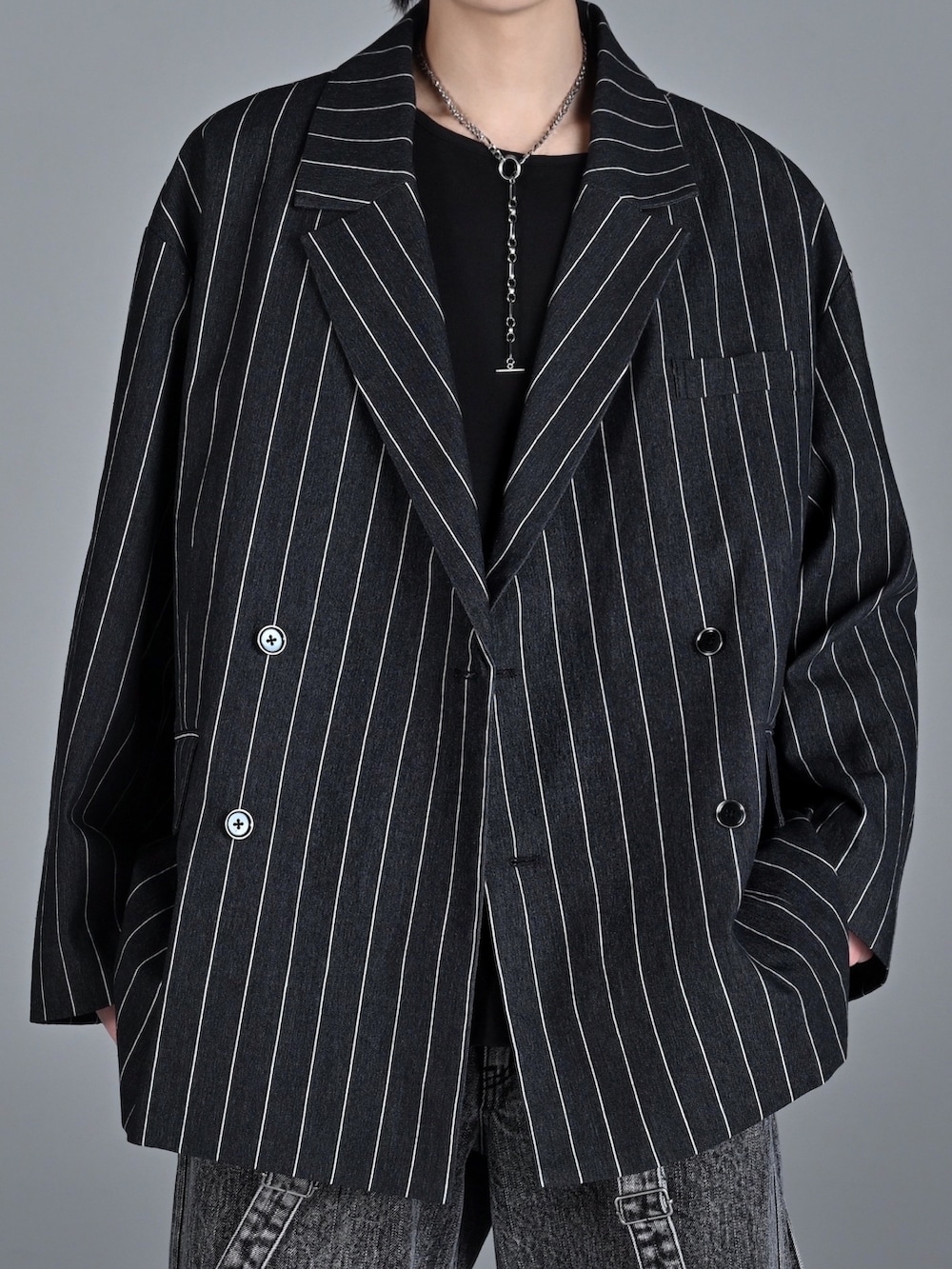 レッド系のタンクトップ、ブラック系のテーラードジャケット、ブラック系のデニムパンツを着用したメンズの冬コーディネートの2枚目の写真