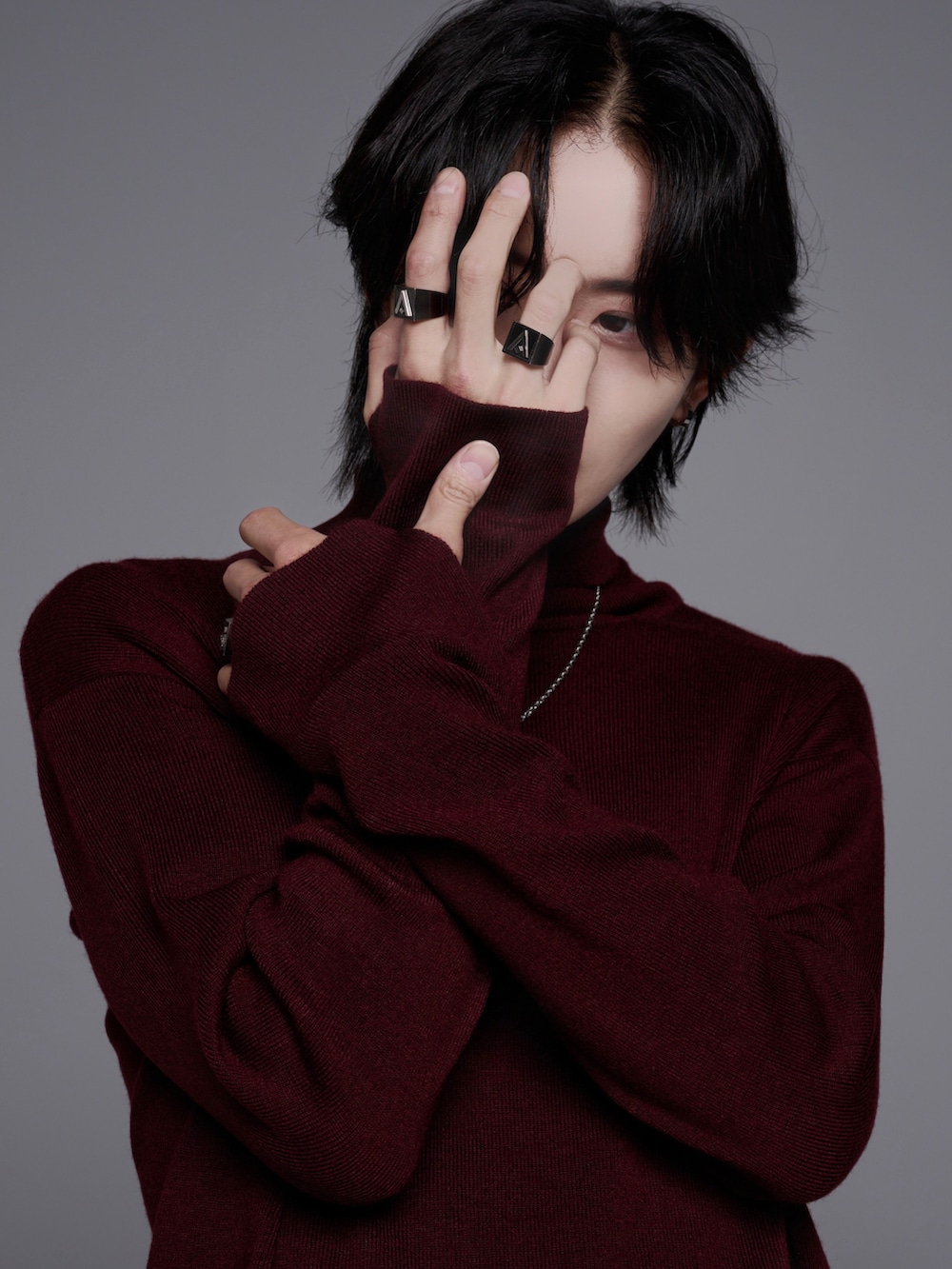 ブラック系のスニーカー、ブラック系のニット/セーター、グレー系のデニムパンツを着用したメンズの秋コーディネートの2枚目の写真