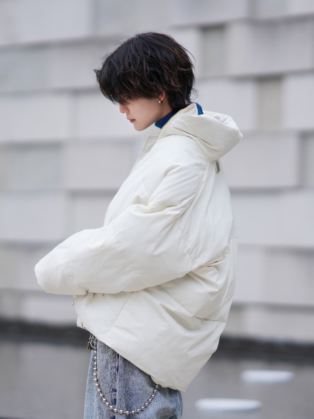 ブルー系のデニムパンツ、グリーン系のニット/セーター、ホワイト系のダウンジャケット/コートを着用したメンズの秋コーディネートの3枚目の写真