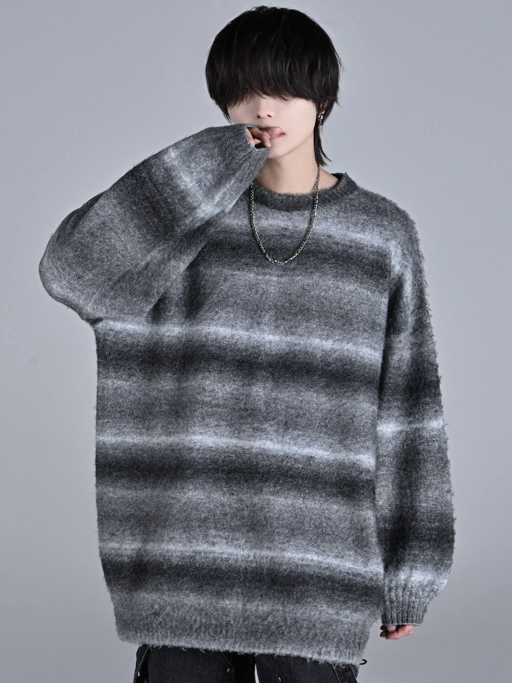 ブラック系のニット/セーター、ブラック系のデニムパンツ、ホワイト系のスニーカーを着用したメンズの秋コーディネートの2枚目の写真