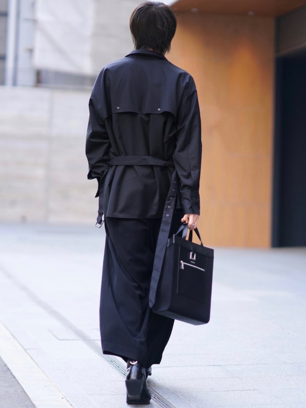 ブラック系のテーラードジャケット、ブラック系のスラックス、ブラック系のブーツを着用したメンズの春コーディネートの5枚目の写真