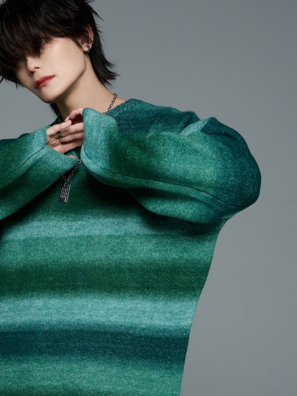 ブラック系のデニムパンツ、ブラック系のブーツ、グリーン系のニット/セーターを着用したメンズの秋コーディネートの5枚目の写真