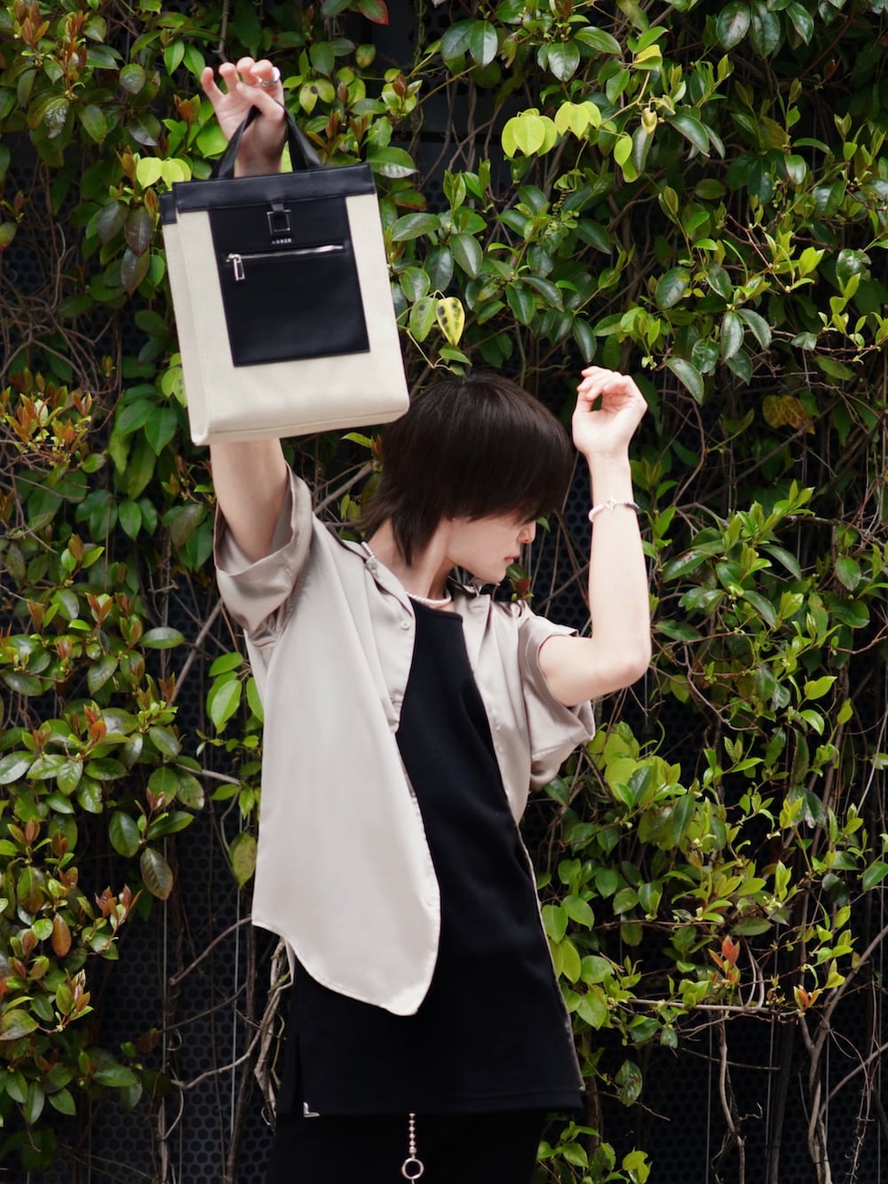 ブラック系のデニムパンツ、ベージュ系のトートバッグ、ブラック系のブーツを着用したメンズの春コーディネートの4枚目の写真