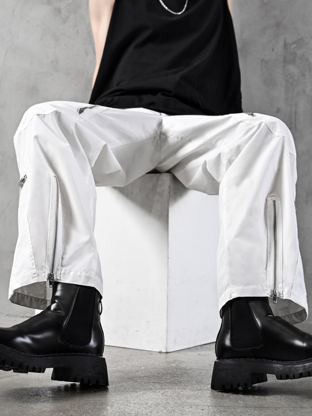 ブラック系のタンクトップ、ホワイト系のデニムパンツ、ブラック系のショルダーバッグを着用したメンズの春コーディネートの4枚目の写真