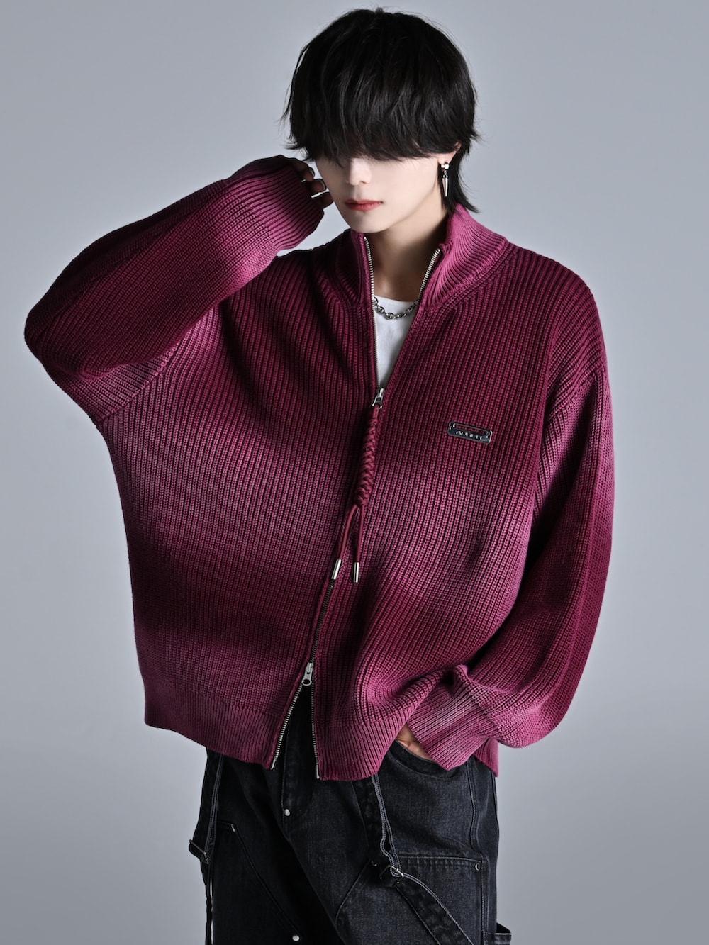 レッド系のニット/セーター、ブラック系のデニムパンツ、ブラック系のスニーカーを着用したメンズの秋コーディネートの2枚目の写真