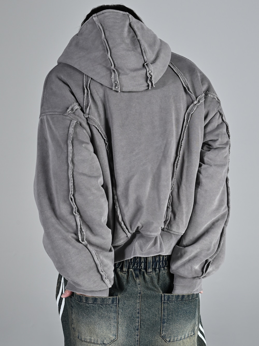 グレー系のパーカー、グレー系のデニムパンツ、ブラック系のローファーを着用したメンズの秋コーディネートの3枚目の写真