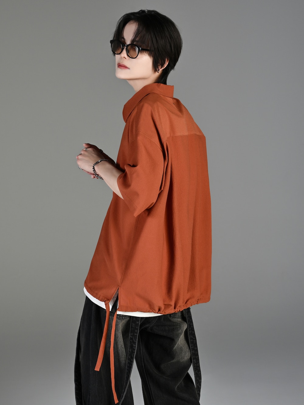 グレー系のタンクトップ、ブラック系のデニムパンツ、ホワイト系のスニーカーを着用したメンズの春コーディネートの4枚目の写真