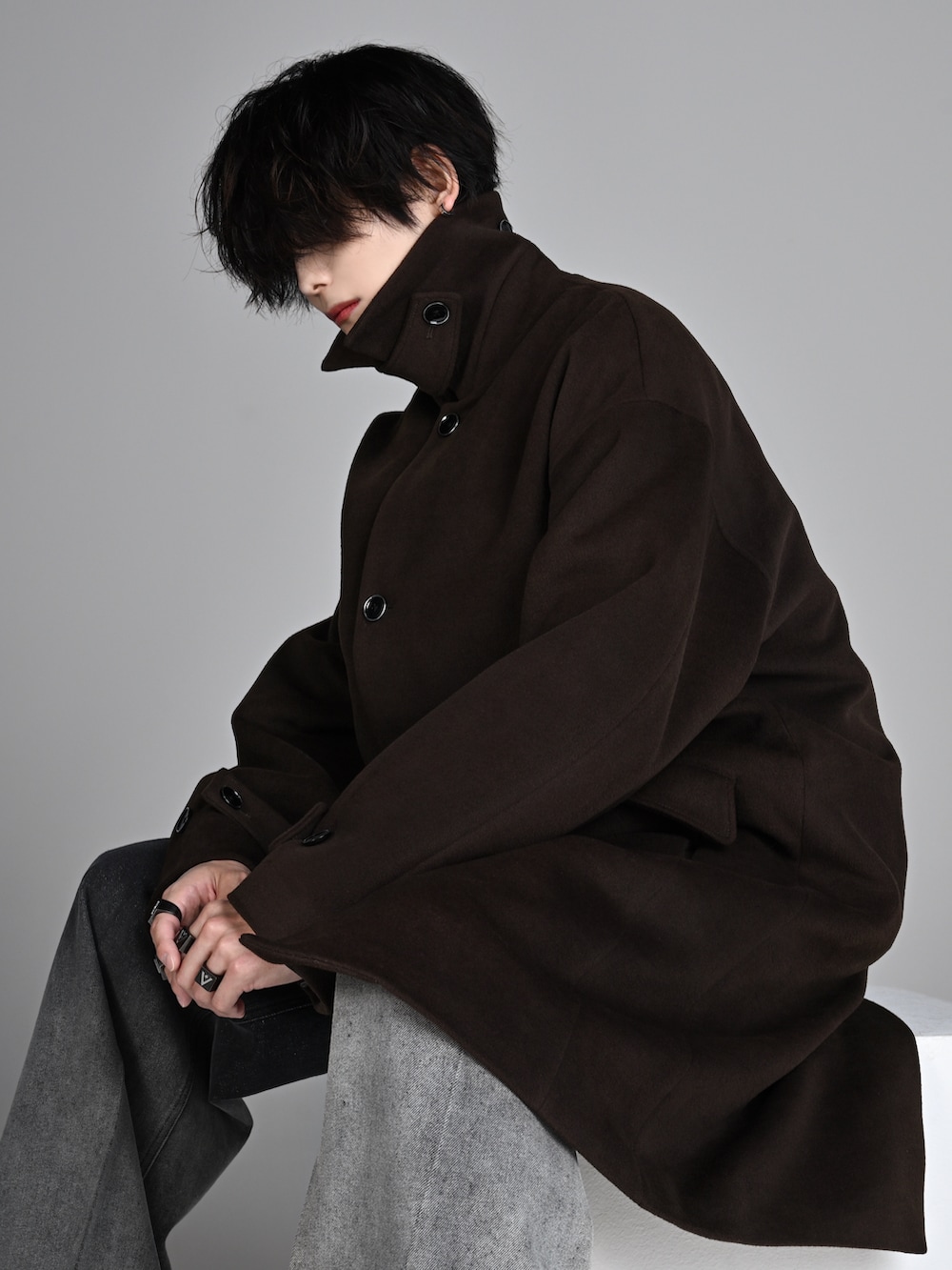 ブラック系のタンクトップ、ブラック系のブーツ、ブラウン系のステンカラーコートを着用したメンズの秋コーディネートの3枚目の写真