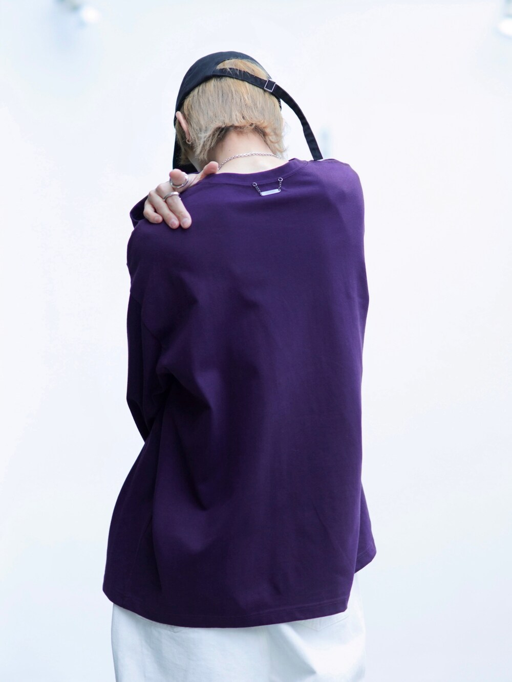 ブラック系のスニーカー、パープル系のTシャツ/カットソー、ホワイト系のデニムパンツを着用したメンズの春コーディネートの4枚目の写真