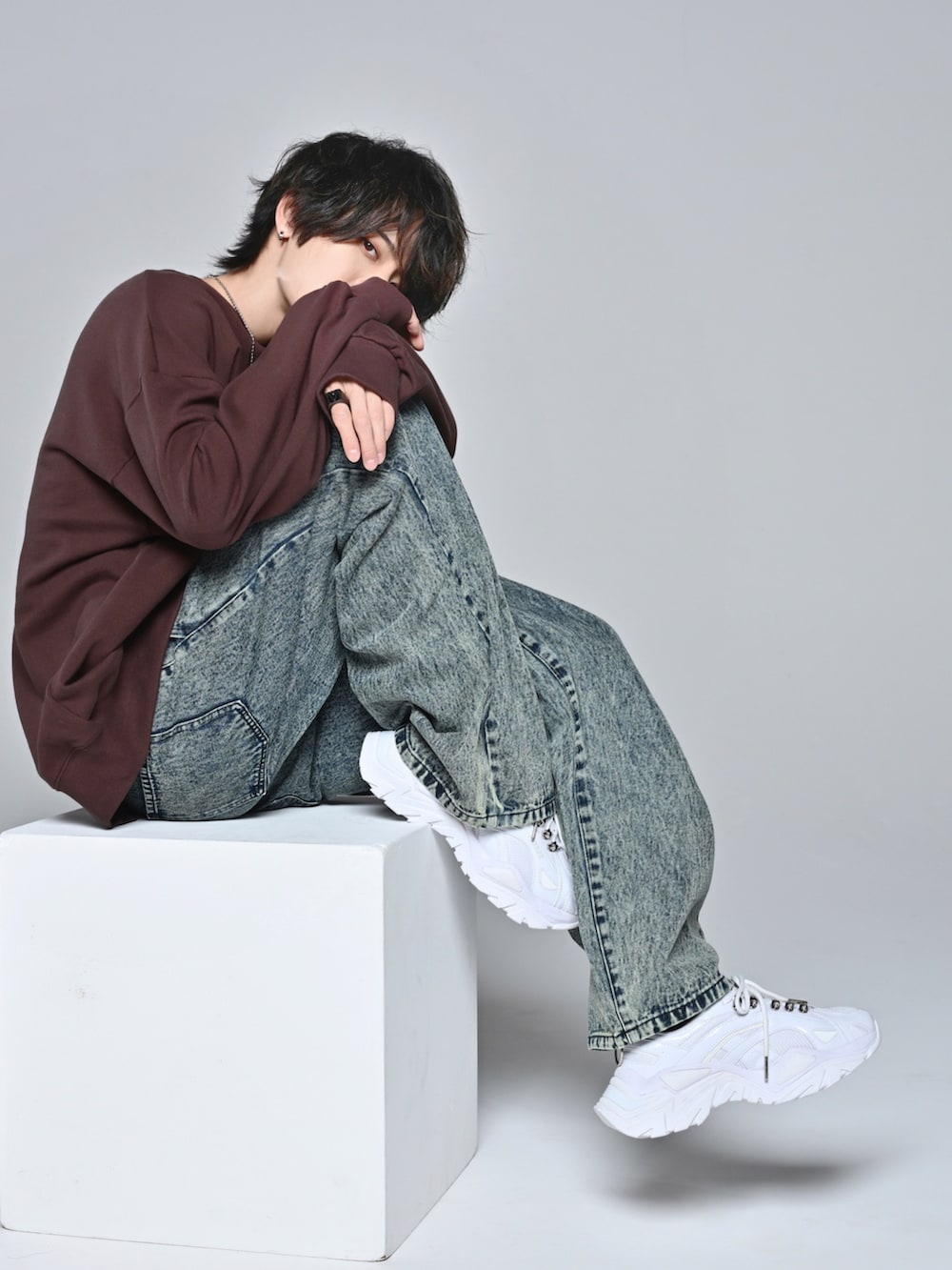 ホワイト系のスニーカー、ブラウン系のスウェット、ベージュ系のデニムパンツを着用したメンズの冬コーディネートの2枚目の写真