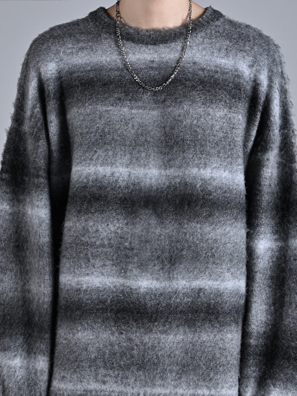 ブラック系のニット/セーター、ブラック系のデニムパンツ、ホワイト系のスニーカーを着用したメンズの秋コーディネートの4枚目の写真