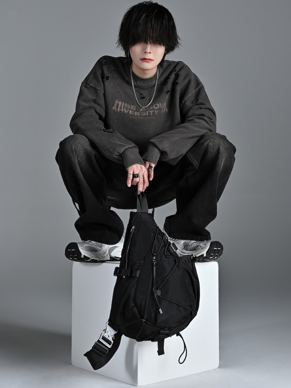 ホワイト系のスニーカー、ブラウン系のスウェット、ブラック系のデニムパンツを着用したメンズの冬コーディネートの2枚目の写真