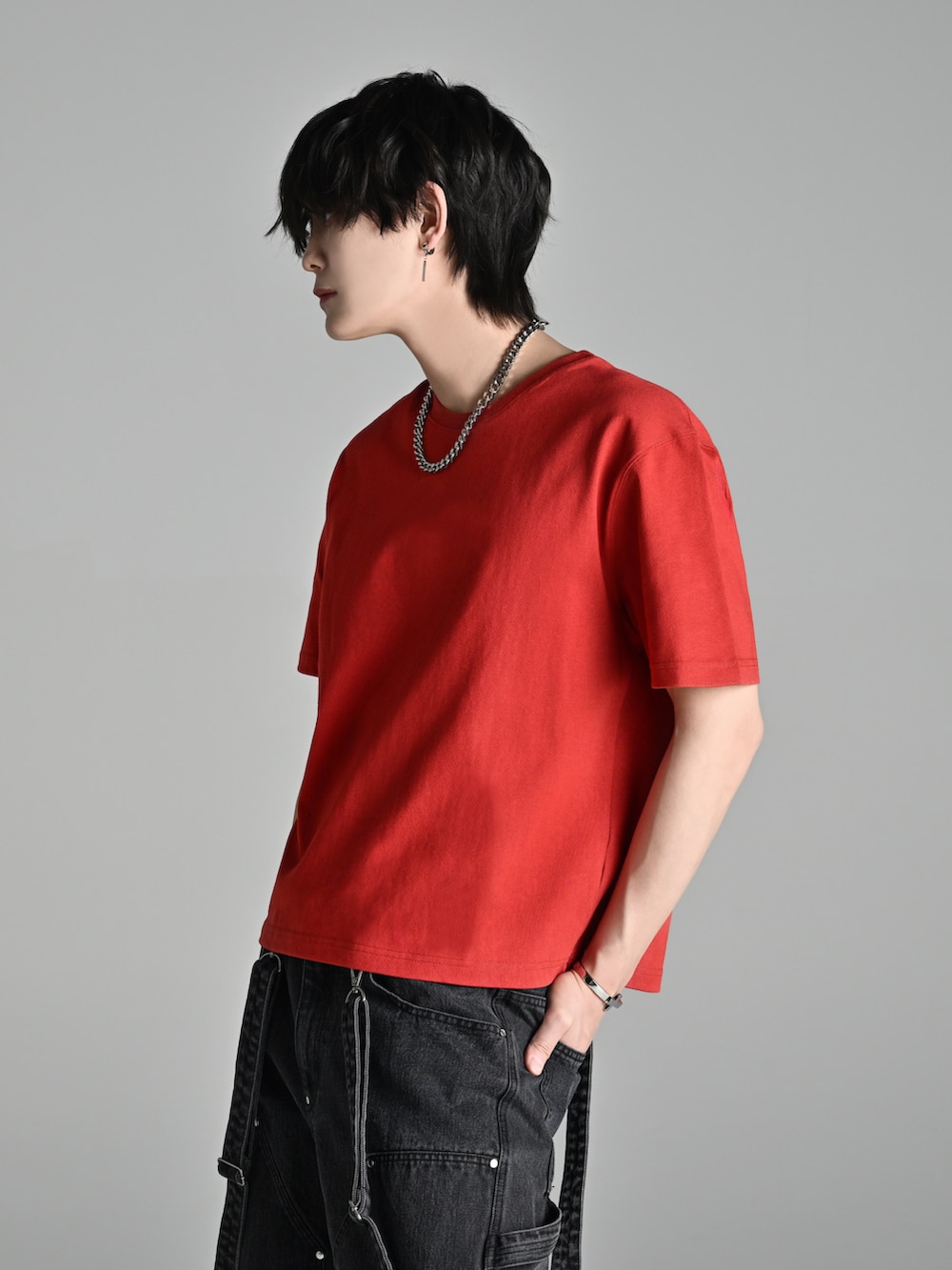 ブラック系のデニムパンツ、レッド系のTシャツ/カットソー、ブラック系のブーツを着用したメンズの春コーディネートの3枚目の写真