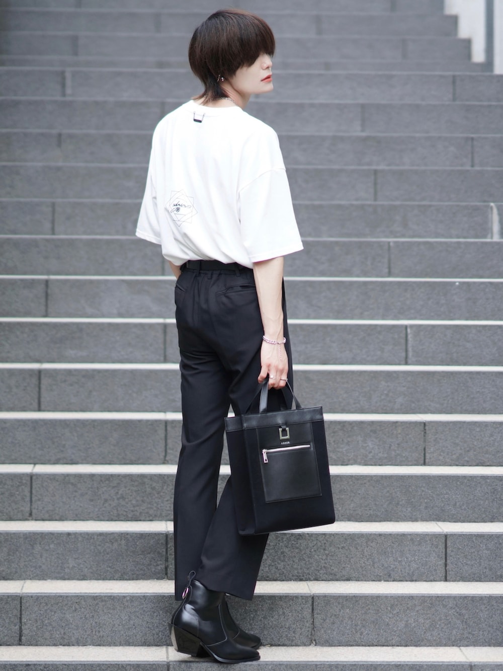 ホワイト系のTシャツ/カットソー、ブラック系のスラックス、ブラック系のブーツを着用したメンズの夏コーディネートの3枚目の写真