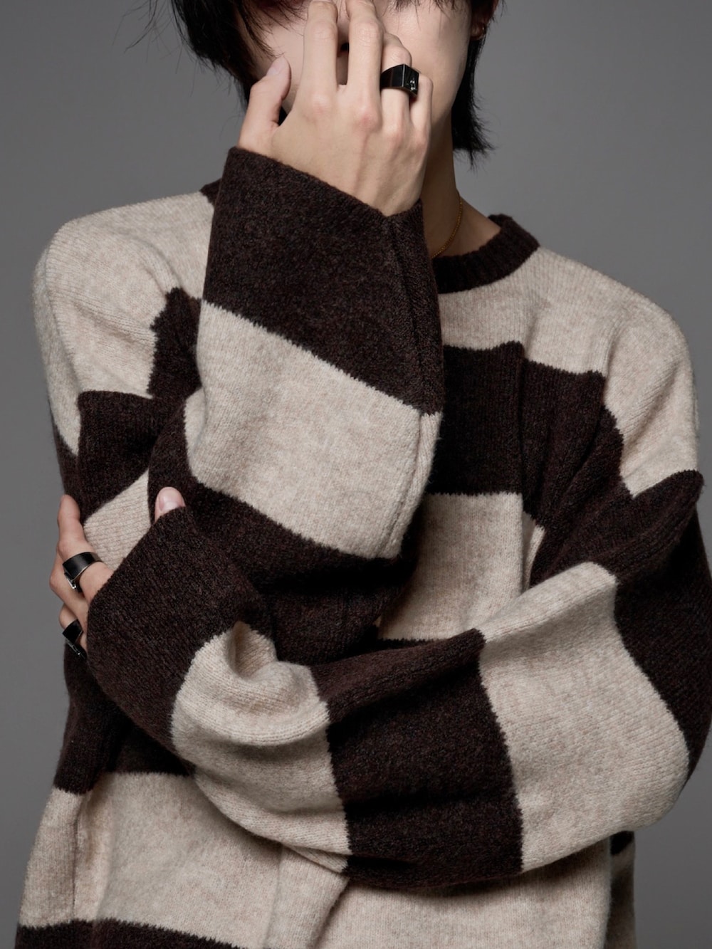 ブラック系のデニムパンツ、ホワイト系のスニーカー、ブラウン系のニット/セーターを着用したメンズの秋コーディネートの5枚目の写真