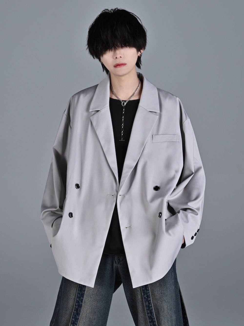 ブルー系のデニムパンツ、レッド系のタンクトップ、グレー系のテーラードジャケットを着用したメンズの冬コーディネートの2枚目の写真