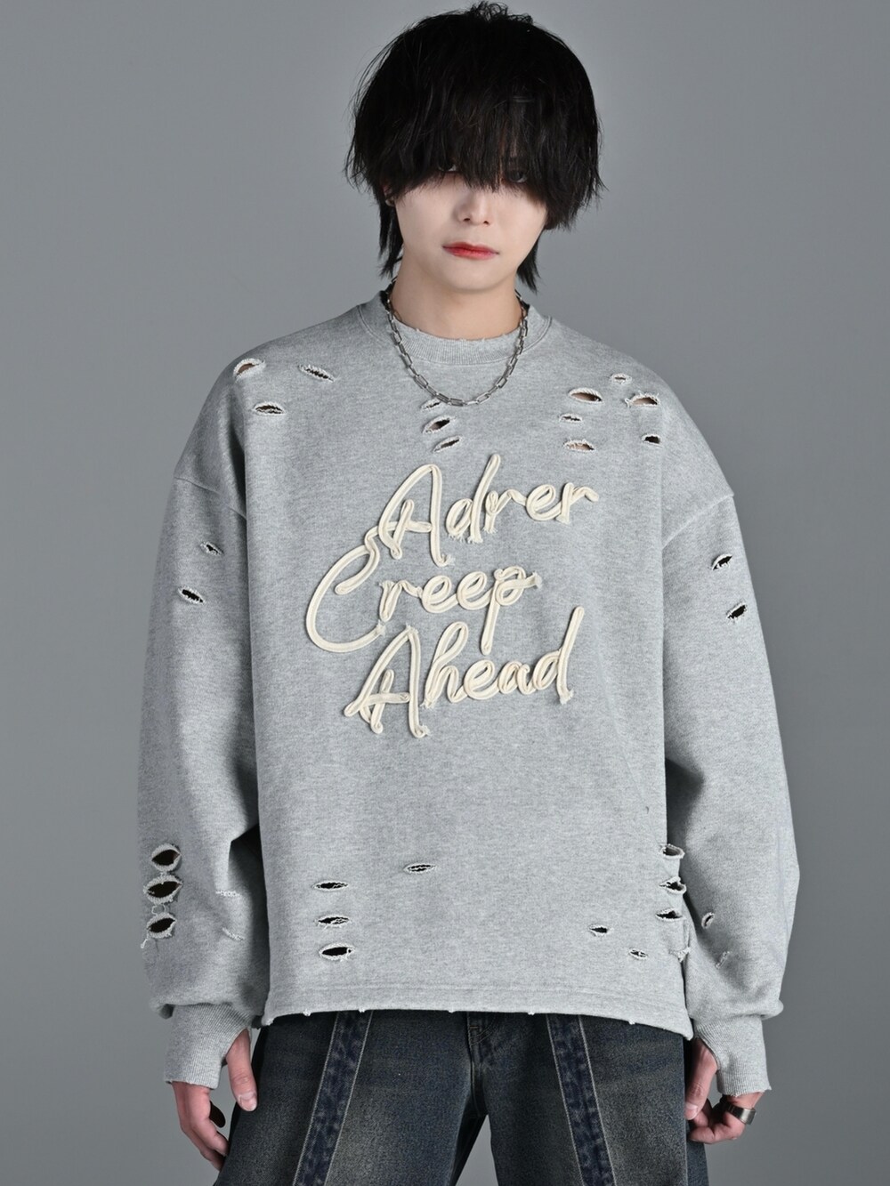 グレー系のスウェット、ブルー系のデニムパンツ、シルバー系のネックレスを着用したメンズの冬コーディネートの2枚目の写真