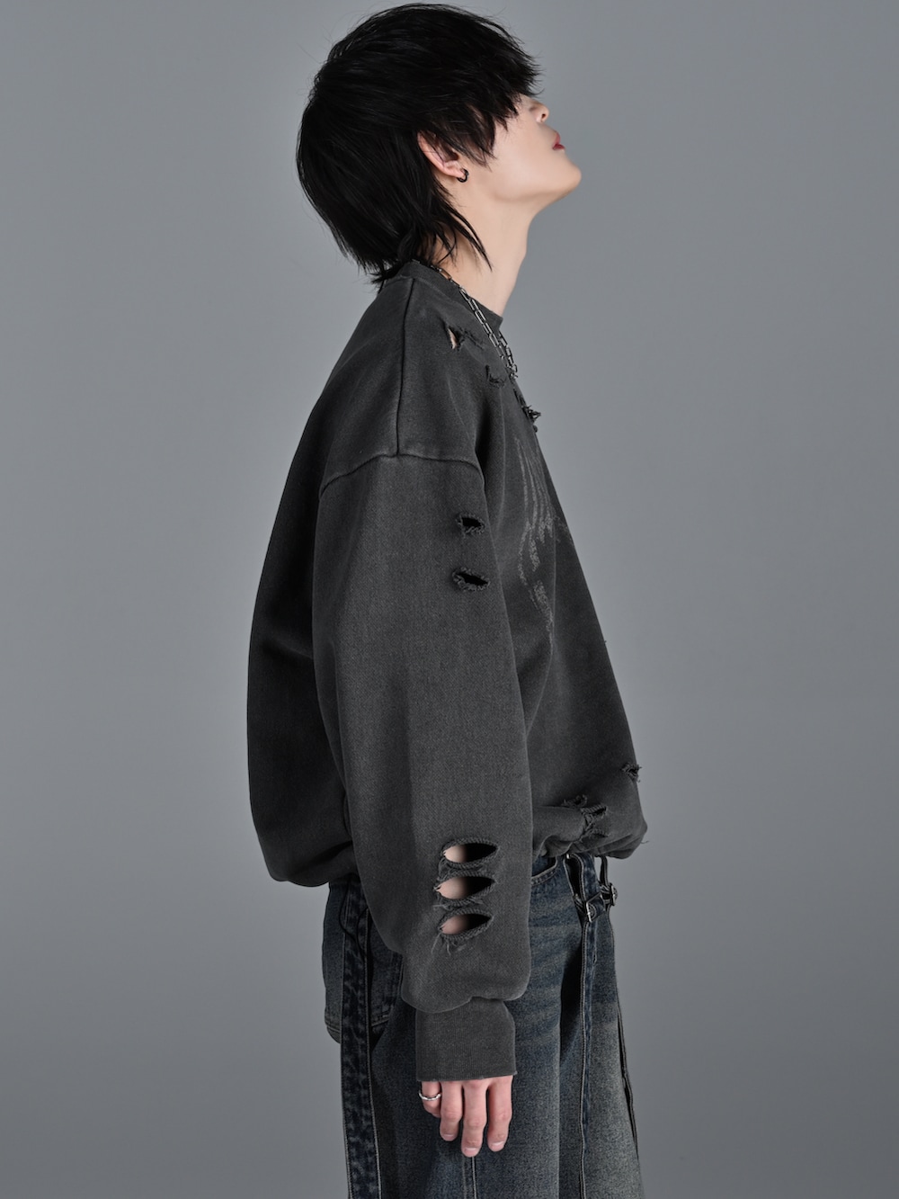 グレー系のスウェット、グレー系のデニムパンツ、シルバー系のネックレスを着用したメンズの冬コーディネートの5枚目の写真