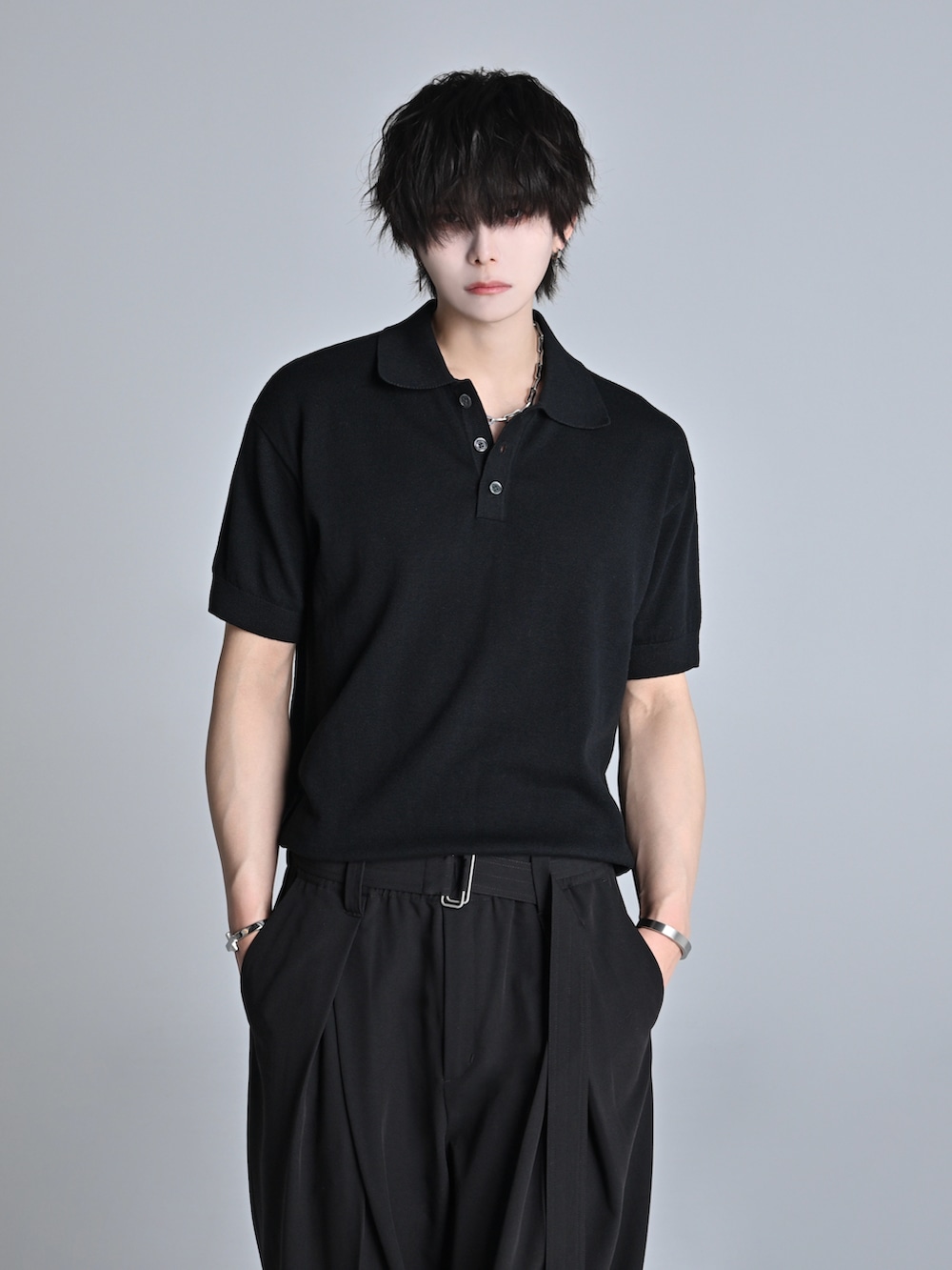 ブラック系のデニムパンツ、ブラック系のポロシャツ、ブラック系のブーツを着用したメンズの春コーディネートの5枚目の写真