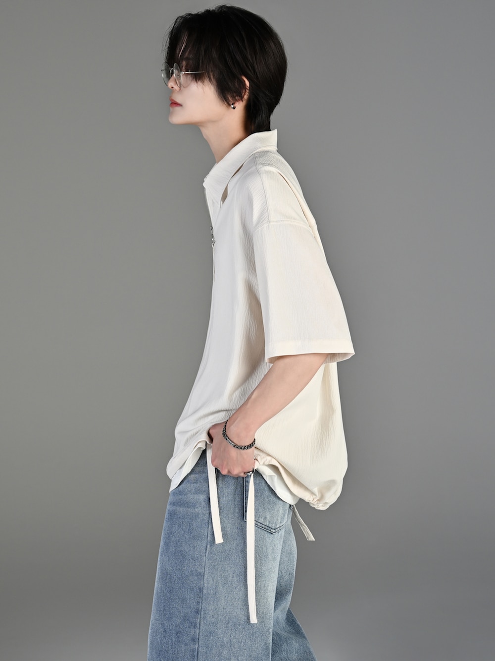 グレー系のタンクトップ、ブルー系のデニムパンツ、ホワイト系のスニーカーを着用したメンズの春コーディネートの3枚目の写真