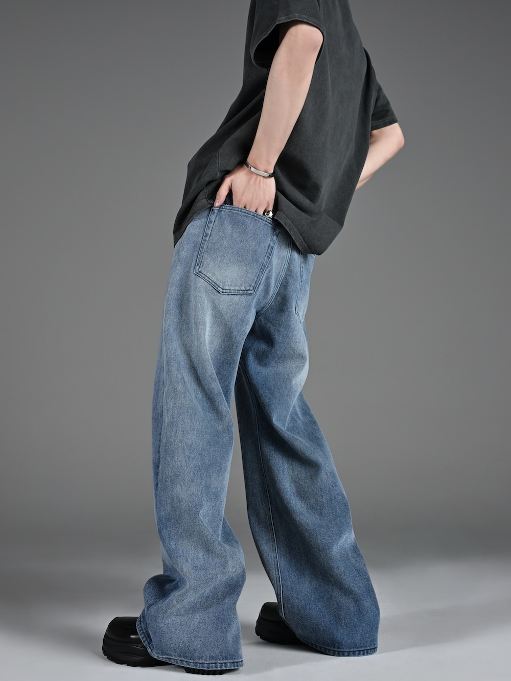 ブラック系のブーツ、グレー系のTシャツ/カットソー、ブルー系のデニムパンツを着用したメンズの春コーディネートの4枚目の写真