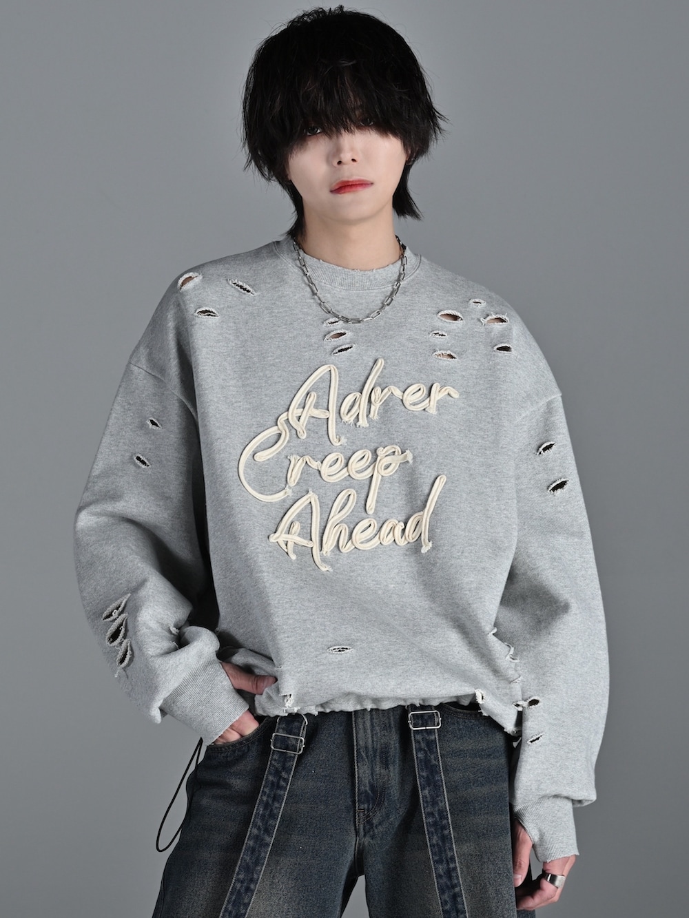 ホワイト系のスニーカー、グレー系のスウェット、ブルー系のデニムパンツを着用したメンズの冬コーディネートの4枚目の写真