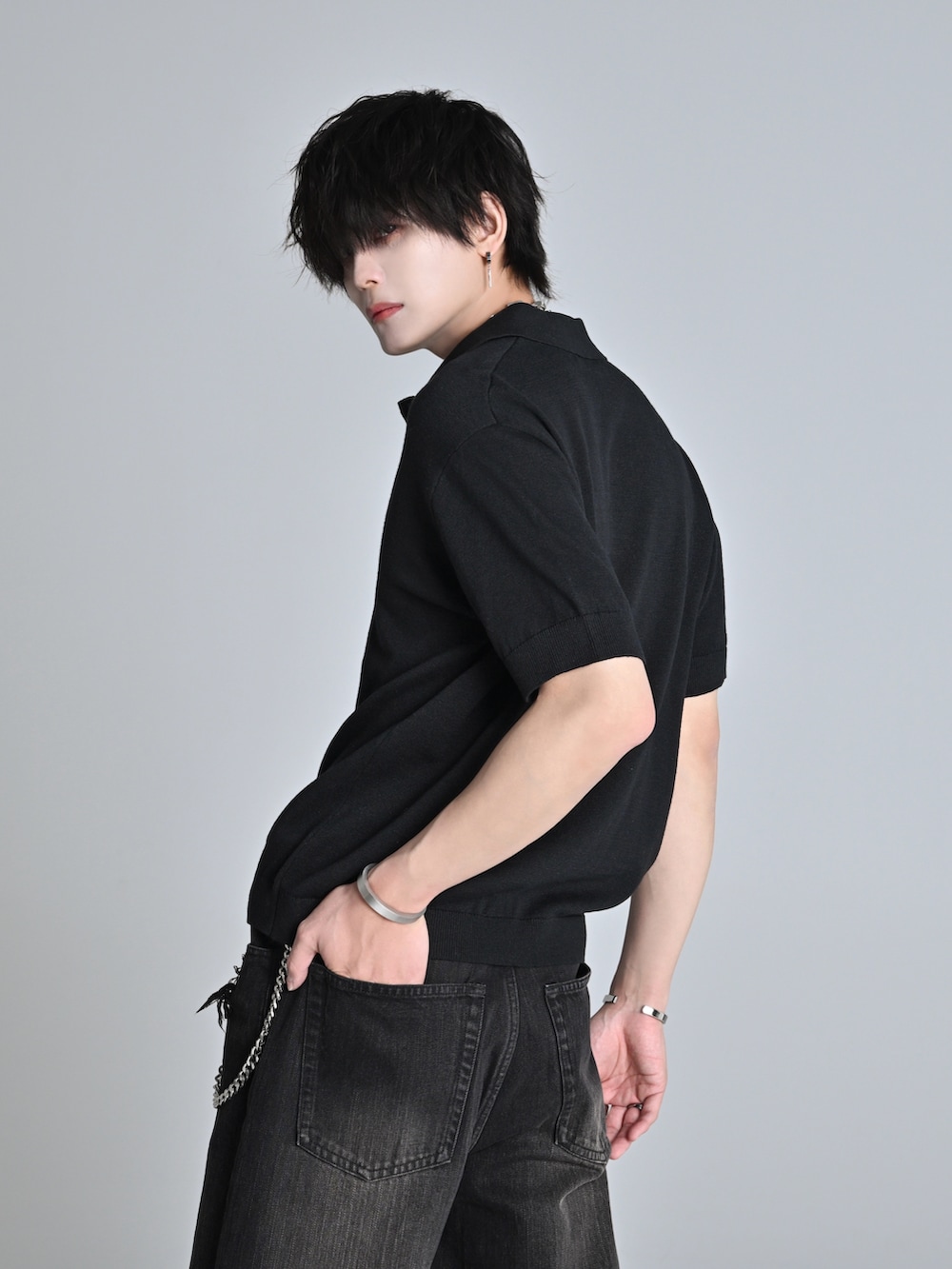 ブラック系のデニムパンツ、ブラック系のポロシャツ、ブラック系のブーツを着用したメンズの春コーディネートの3枚目の写真