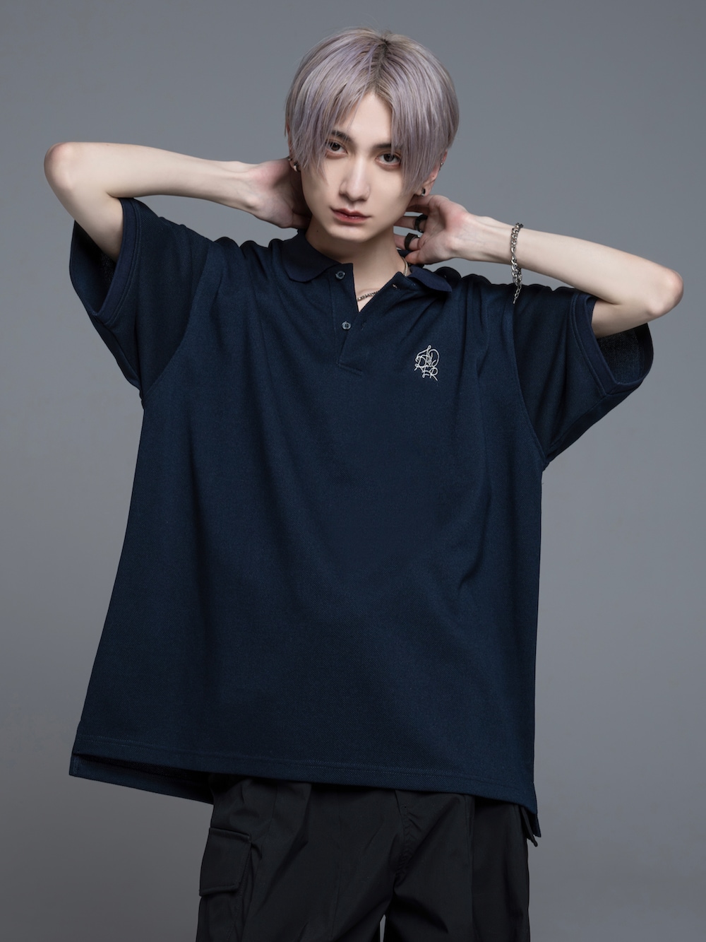 ブラック系のデニムパンツ、ブラック系のブーツ、ホワイト系のポロシャツを着用したメンズの春コーディネートの2枚目の写真